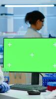 Researcher looking at chroma key display in modern equipped lab analysing virus evolution. Team of microbiologists doing vaccine research writing on device with green screen, isolated, mockup display. photo