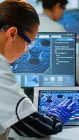 Scientist using digital tablet working in modern medical research laboratory, analyzing DNA information. Medicine, biotechnology research in advanced pharma lab, examining virus evolution photo
