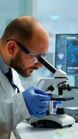 Male scientist looking under microscope in medical development laboratory, entering data in computer. Specialists working on medicine, biotechnology research in advanced pharma lab photo