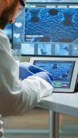 Biochemist checking manifestations of virus looking in tablet with special software in chemistry laboratory. Group of doctors examining vaccine evolution using high tech researching diagnosis photo