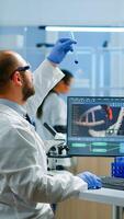 Medical scientist working with DNA scan image in modern equipped laboratory holding test tube with sample. Team examining vaccine evolution using high tech and chemistry tools for vaccine development photo