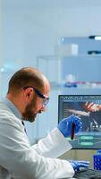 Laboratory medical stuff disscussing about vaccine development holding test tube with blood sample. Medical scientist working with DNA scan image in modern equipped laboratory using high tech photo