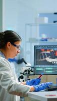 Team of microbiology scientists discussing about virus development in modern equpped laboratory using computer analysing test blood samples and develop vaccine, drugs and antibiotics against covid-19. photo