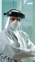 Portrait of tired scientist in coverall looking at camera sitting in modern equipped laboratory. Team of doctors examining virus evolution using high tech and chemistry tools for vaccine development. photo