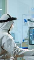 Medical scientist in ppe suit working with DNA scan image typing on pc in equipped laboratory. Examining vaccine evolution using high tech and chemistry tools for scientific research virus development photo