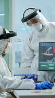 Scientist team in prorection suit arguing in front of pc looking at virus development in equipped laboratory.Team of scientists analysing vaccine evolution using high tech for researching treatment photo