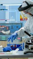Doctor with coverall working with blood samples in laboratory typing on pc. Team of chemists examining vaccine evolution using high tech for research in treatment development against covid19 virus photo