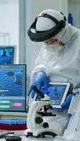 Team of scientists in coveall discussing about virus development in front of pc and tablet in equipped laboratory. Medical stuff analysing vaccine evolution using high tech for researching treatment photo