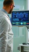 Scientist worried about virus evolution analysing DNA scan image standing in equipped laboratory typing at computer. Stuff examining vaccine development using high tech researching treatment photo