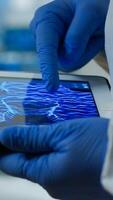 Close up of chemist doctor working on tablet with DNA scan image analysing treatment results. Scientist examining virus evolution using high tech researching vaccine development against covid19 photo