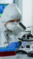 Woman scientist in ppe suit working in lab using modern microscope with slides. Team of chemists researcher examining virus evolution using high tech for vaccine scientific research against covid19 photo