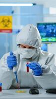Science technician in ppe suit using micropipette and petri dish working in research laboratory analysing blood sample. Team examining virus evolution for vaccine development against covid19 photo