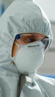 Scientist in coverall doing research analysing liquid in tube at modern equipped laboratory. Biochemist examining vaccine evolution using high tech for treatment development against covid19 virus photo
