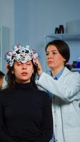 Asistance of neurological doctor putting eeg headset on patient head scaning brain functions, descovering diagnosis of disease. Team of scientists researchers working late night in neurology clinic photo