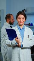 Portrait of scientist neurologist researcher looking at camera smiling while coworker discussing with patient in background about brain functions, nervous system, tomography scan working in laboratory photo