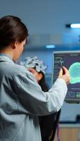 Researcher looking at monitor analysing brain scan while coworker discussing with patient in background about side effects, mind functions, nervous system, tomography scan working in laboratory photo
