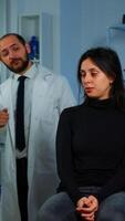 Woman waiting doctor sitting on chair in neurological research laboratory, while researchers team discussing in background health status of patient, brain functions, nervous system, tomography scan photo