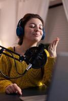 Social media influencer blowing kisses at camera for fans while recording livestream answering listeners questions in living room studio. Vlogger hosting online entertainment vlog. On-air show photo