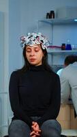 Specialist neurologist doctor taking notes on laptop asking patient's symptoms adjusting high tech eeg headset. Doctor researcher controlling EEG headset analyzing brain functions and health status photo