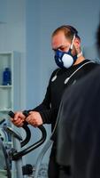 Patient making electrocardiogram during physical exercise in sports science lab, monitoring endurance and heart rate, computer showing EKG data on display. Man running with mask and medical electrodes photo