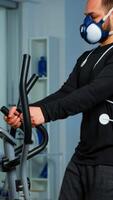 Performant sportsman measuring heart rate with performant ekg equipment in sports science laboratory running on cross trainer, while medical researcher typing on tablet. Doctor using body sensor photo