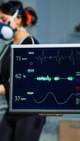 Monitor showing EKG scan of athlete running on cross trainer and medical specialists supervise exercise in background, controlling physical activity, measuring heart rate in sports science laboratory photo