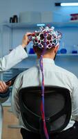Man patient wearing performant eeg headset scanning brain electrical activity in neurological research laboratory while medical researcher controlling it, examining nervous system, nurse taking notes photo