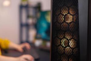 Closuep of gaming pc with rgb led lights standing on table. Gamer woman playing space shooter videogames during online competition. Studio equipped with professional streaming setup photo