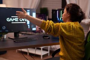 Angry competitive losing space shooter videogames during online entertainment championship at home in living room. Game over on computer screen. Player performing cybersport competition photo