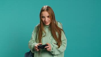 Euphoric woman playing intense gaming console game, celebrating win, studio background. Ecstatic young girl using controller, excited after being victorious in videogame, camera A photo