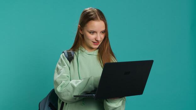 Joyful woman adding payment method on website using laptop, enjoying sales period, studio background. Girl doing purchases on internet, typing credit card information on notebook, camera A photo