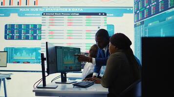 Financial analyst works on resource allocation plans with his staff, analyzing reports and sales infographics to find revenue. Achieve objectives in a competitive business environment. Camera B. photo