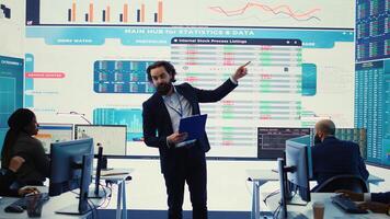 Teammates and manager assembling in a big data room to go over their results, examining graphic representations with feedback from shareholders investors. Exchanging perspectives. Camera B. photo