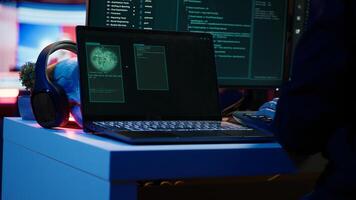 Hooded script kiddie taking laptop out of suitcase, prepared to launch DDoS attack. Close up shot of scammer at computer desk getting notebook from bag, starting work on malware script, camera A photo