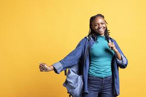 Smiling african american teenager having fun, dancing on rhythm, enjoying leisure time. Jolly BIPOC girl entertaining herself doing funky movements on music, studio background photo