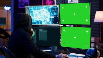Rogue computer scientist uses AI deep learning and green screen PC to develop malware. Hacker uses artificial intelligence neural networks and chroma key monitors to build script, camera A photo