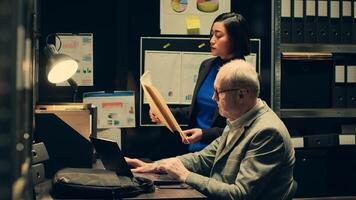 Detective team examines archived files for crucial case evidence, working in incident room with classified documents. Inspectors remain relentless in the pursuit of justice, police archive. Camera A. photo