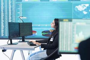 Enterprise analyst reviewing infographics numbers on a big screen at workstation, achieving strategic objectives in a competitive corporate environment. Employee improving efficiency. photo