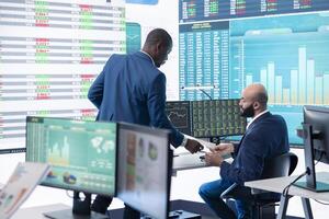Financial manager briefing his team members about new corporation objectives, presenting their budget scheme with expenses. Resource allocation and project planning in control room. photo