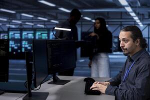 Software developer in server farm tasked to oversee supercomputers used for managing databases. IT expert in data center workspace location doing maintenance on rackmounts storing information photo