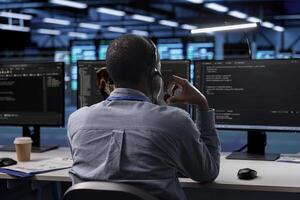 Technician in server room managing call center tasks, speaking into headset while monitoring multiple computer screens. Employee talking with clients through headphones mic photo
