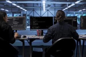 Computer operators in data center running system diagnostic tests to do repairments. IT specialists at PC desk in server room deploying error checking utilities to fix network issues photo
