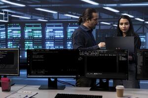 IT experts in server hub ensuring valuable data remains shielded from potential threats using laptop. Employees safeguarding data center against unauthorized access and vulnerabilities photo