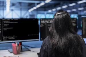 Software developer in server hub establishment ensuring data remains shielded from potential threats. Employee at PC desk safeguarding data center against unauthorized access photo