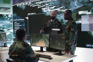 Army conscripts discussing with the IT technical engineer to ensure maneuver and mobility support operations. Employs real time data from radar surveillance systems, military defense program in base. photo