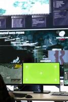 Military specialist monitoring warships traffic activity along the national coast, uses green screen to ensure safety. Professional IT operator working in power base command post. photo
