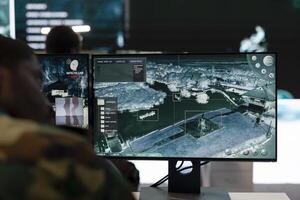 Recruit analyzes satellite radar CCTV footage in control room, monitoring the infantry unit during a battle. Army soldier working in the reconnaissance and defense division command post. photo
