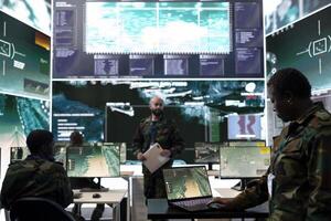 Female trooper working with federal reconnaissance satellite system in command center power base, examining real time battlefield data for the infantry units. Operator in general headquarters. photo