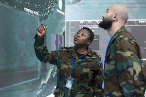 Male and female engineers talking about a new operation next to a big screen, examining real time satellite surveillance data. Military IT operators work on telecommunications. photo