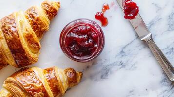 Freshly Baked Croissant with Strawberry Jam on White Marble Background photo